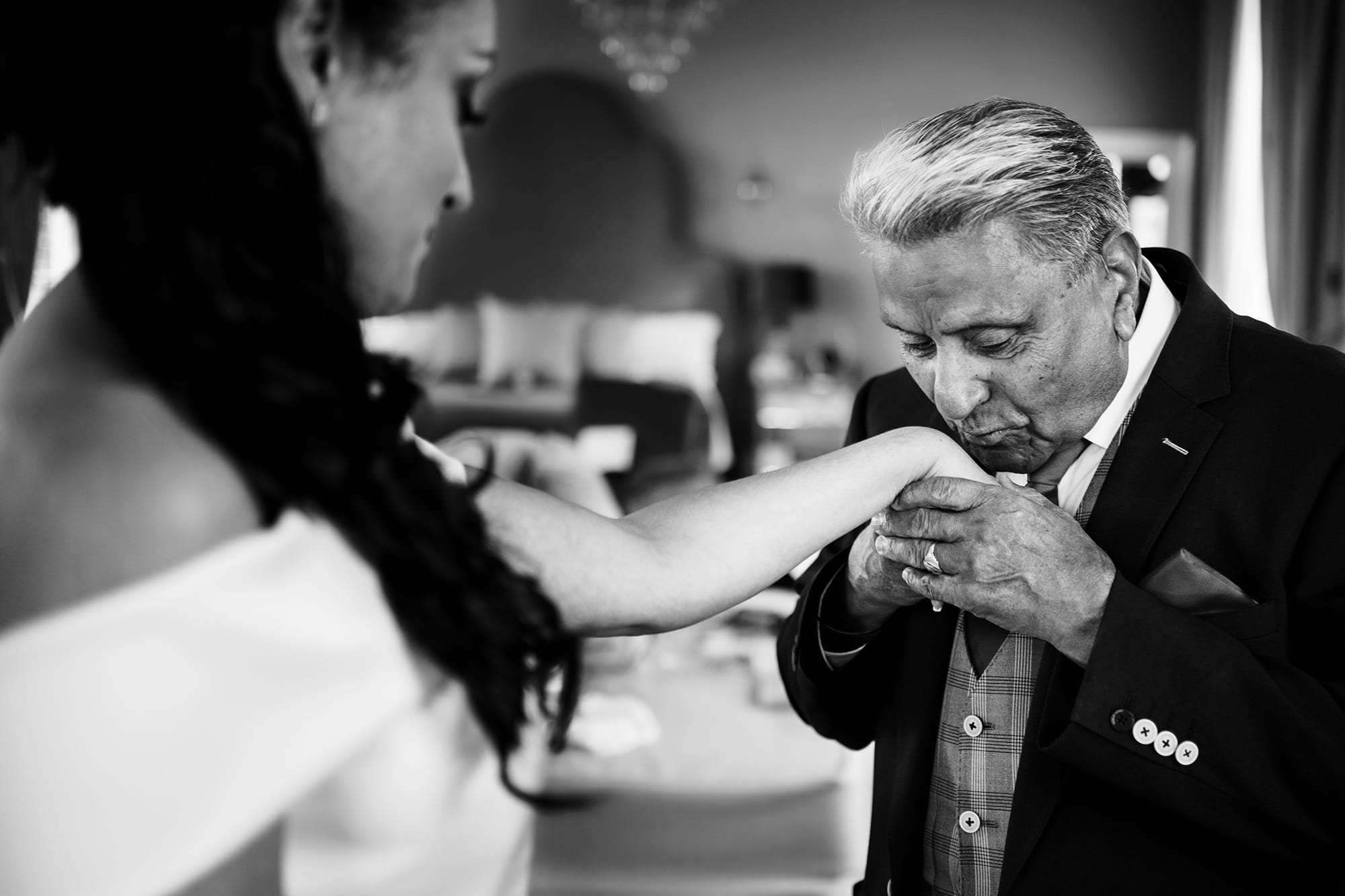Father of the bride kissing his daughter's hand during a candid moment