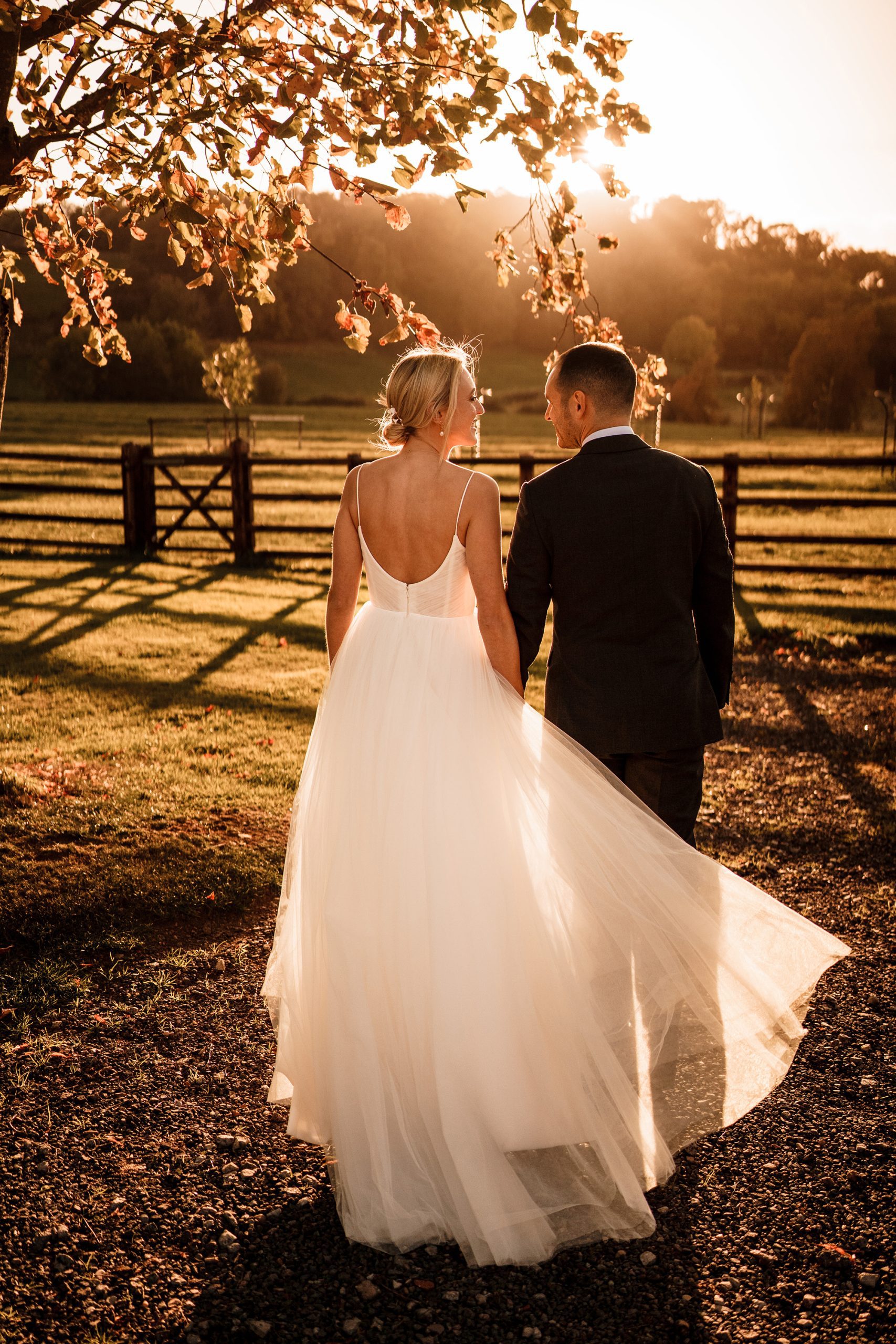 Bride and groom walking together in warm sunset light on wedding day